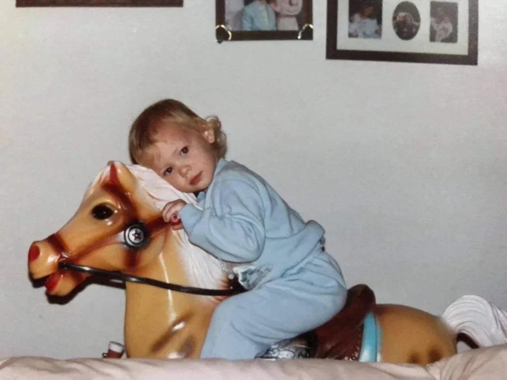 Ansley as a child on a rocking horse